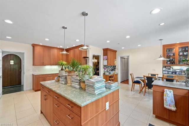 kitchen featuring pendant lighting, light stone counters, a center island, and light tile patterned flooring