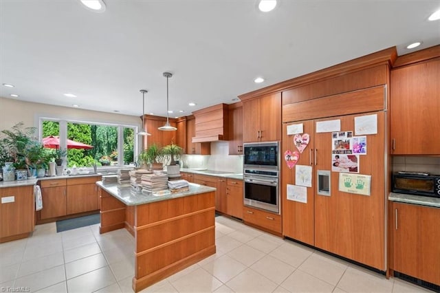 kitchen featuring premium range hood, a center island, hanging light fixtures, decorative backsplash, and black appliances