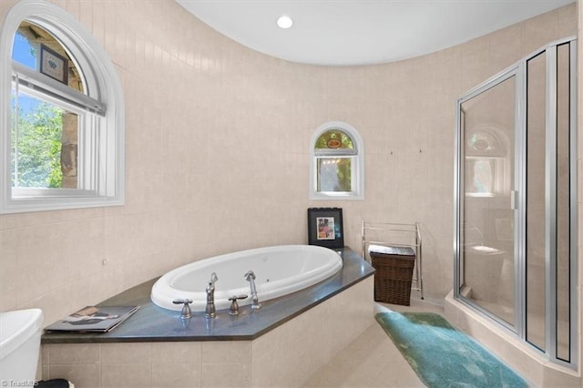 bathroom with independent shower and bath, tile patterned flooring, and tile walls