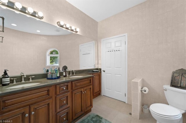 bathroom featuring vanity, toilet, tile patterned flooring, and tile walls