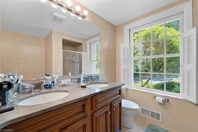 bathroom featuring walk in shower, tile patterned floors, toilet, tile walls, and vanity