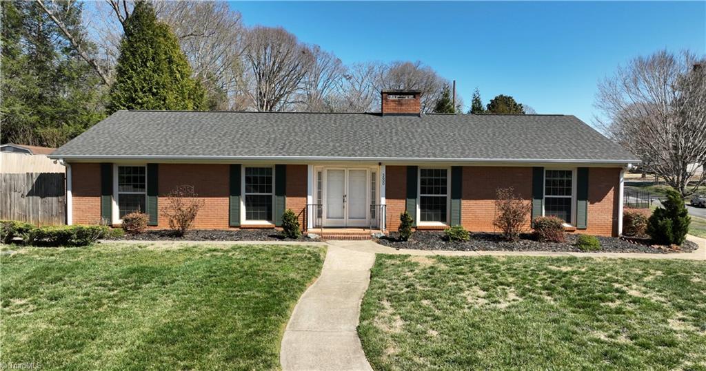 5600 Kane Dr, Pfafftown, NC 27040 - ranch-style home featuring a front lawn, fence, brick siding, and a chimney