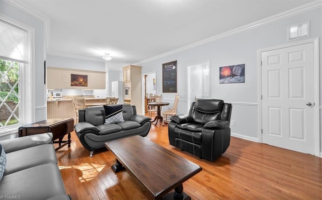living area featuring crown molding, light wood-style floors, and baseboards