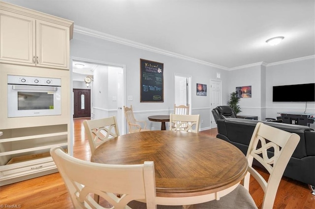 dining space with light wood-style flooring and ornamental molding