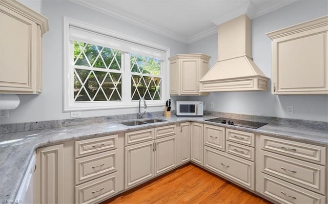 kitchen featuring custom range hood, a sink, cream cabinets, black electric stovetop, and white microwave