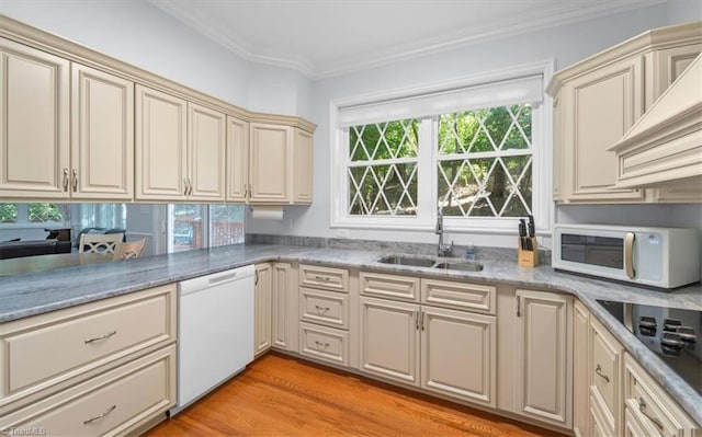 kitchen with ornamental molding, white appliances, cream cabinets, and a sink