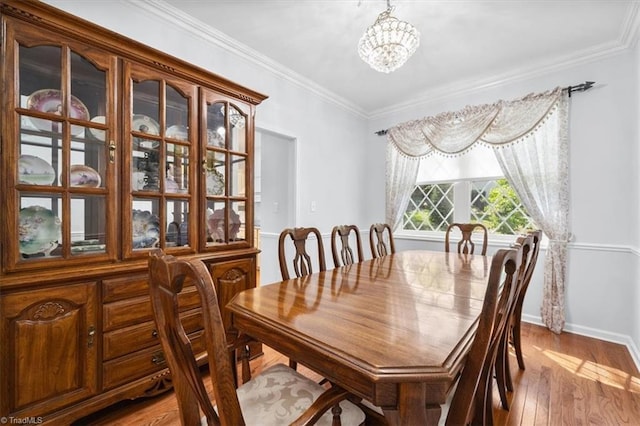 dining room featuring crown molding, a notable chandelier, baseboards, and light wood finished floors