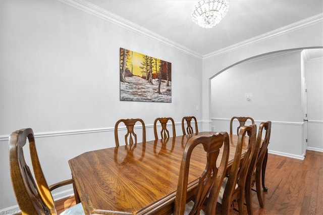 dining space featuring baseboards, ornamental molding, wood finished floors, arched walkways, and a notable chandelier