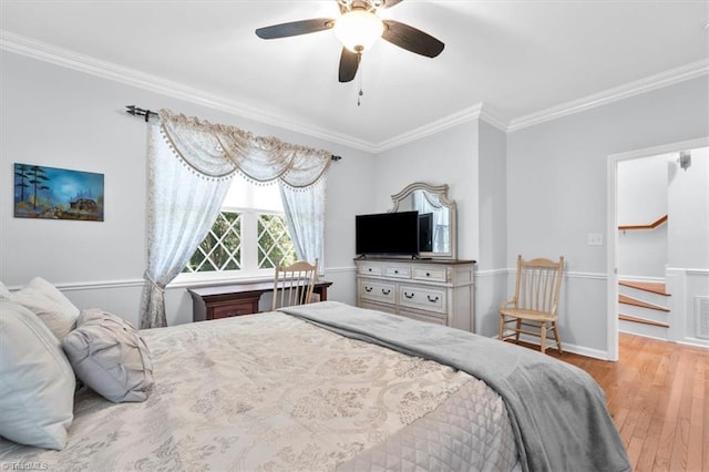bedroom with a spacious closet, crown molding, a ceiling fan, and wood finished floors