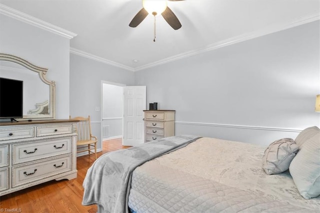 bedroom with crown molding, wood finished floors, visible vents, and ceiling fan