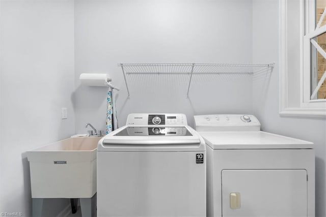 clothes washing area with laundry area, separate washer and dryer, and a sink