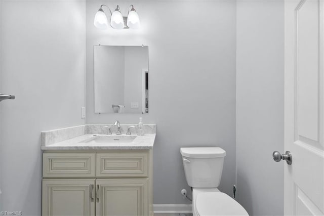 half bath with baseboards, toilet, and vanity