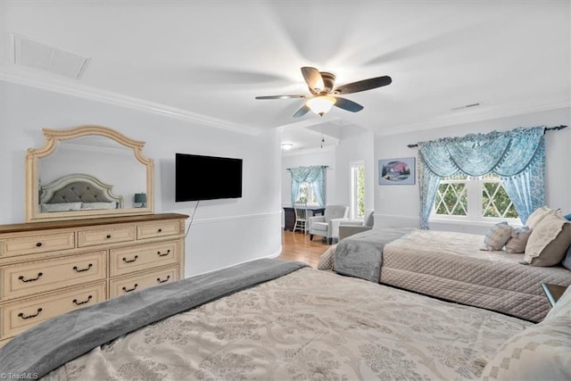 bedroom featuring wood finished floors, ornamental molding, and a ceiling fan