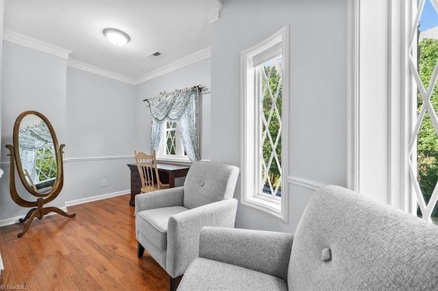 living area featuring visible vents, wood finished floors, baseboards, and ornamental molding
