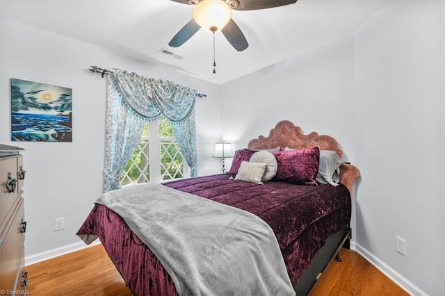 bedroom featuring visible vents, baseboards, wood finished floors, and a ceiling fan