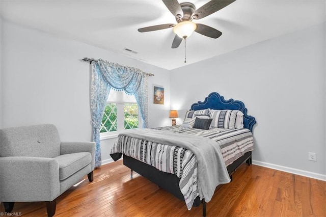 bedroom with visible vents, wood-type flooring, baseboards, and a ceiling fan