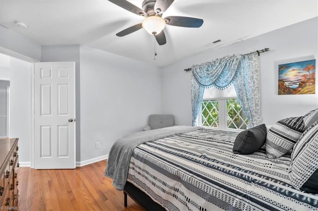 bedroom featuring light wood-style flooring, baseboards, visible vents, and ceiling fan