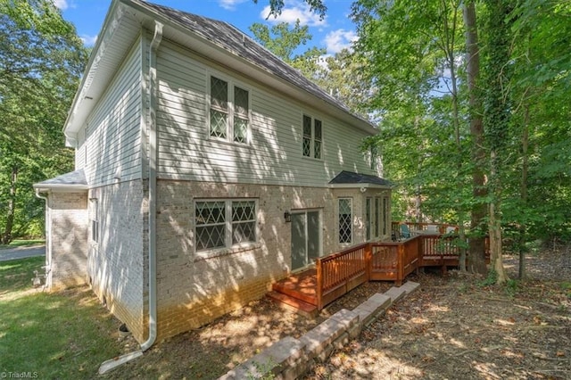 rear view of house with brick siding and a wooden deck