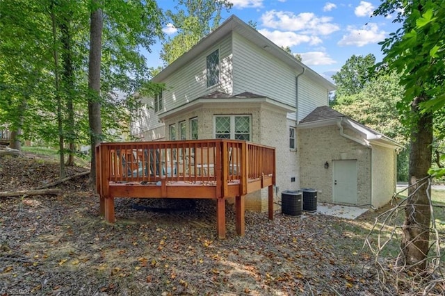 back of house with a deck, central air condition unit, and brick siding