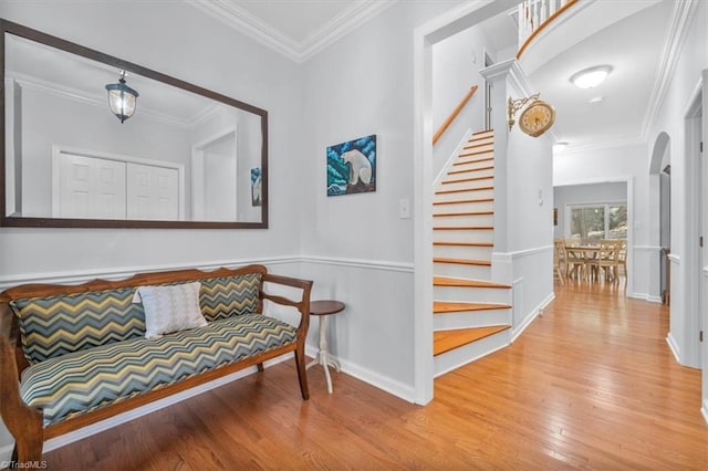 interior space with ornamental molding, wood finished floors, stairway, arched walkways, and baseboards