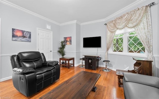 living area with hardwood / wood-style flooring, crown molding, baseboards, and visible vents