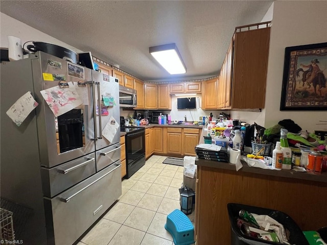 kitchen with appliances with stainless steel finishes, sink, a textured ceiling, and light tile patterned floors