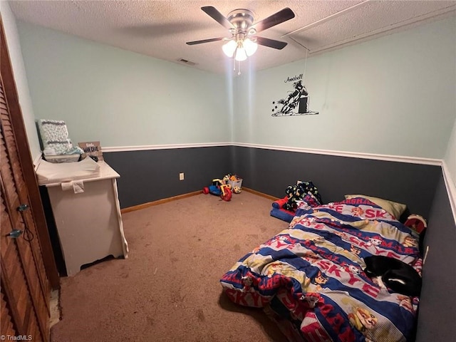 carpeted bedroom featuring ceiling fan and a textured ceiling