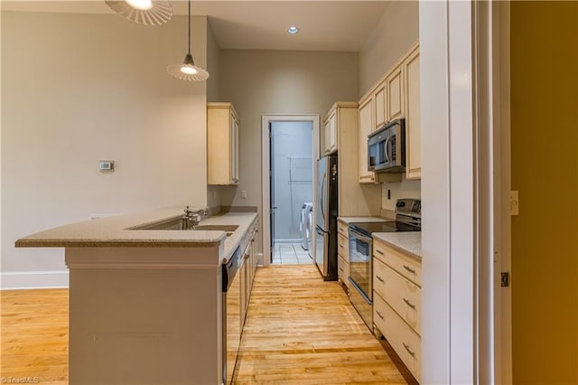 kitchen with a sink, appliances with stainless steel finishes, a peninsula, and light wood finished floors