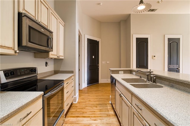 kitchen with light brown cabinets, light wood-style flooring, appliances with stainless steel finishes, and a sink