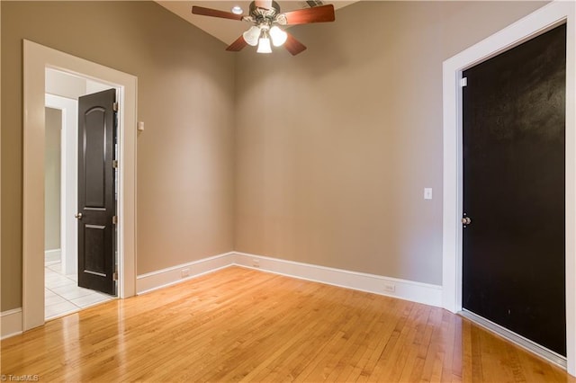 spare room featuring baseboards, ceiling fan, and light wood finished floors