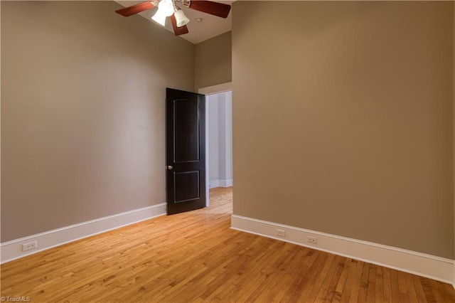 empty room with ceiling fan, light wood-style floors, and baseboards