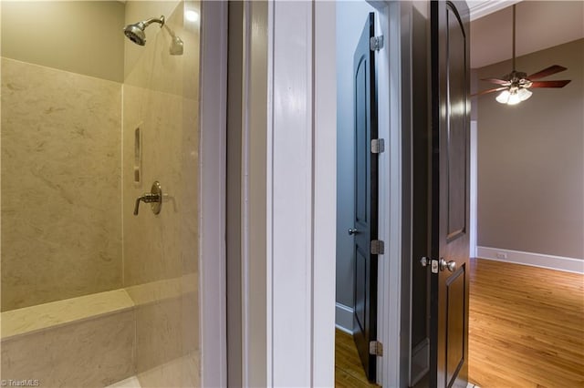 full bathroom featuring ceiling fan, wood finished floors, and a tile shower