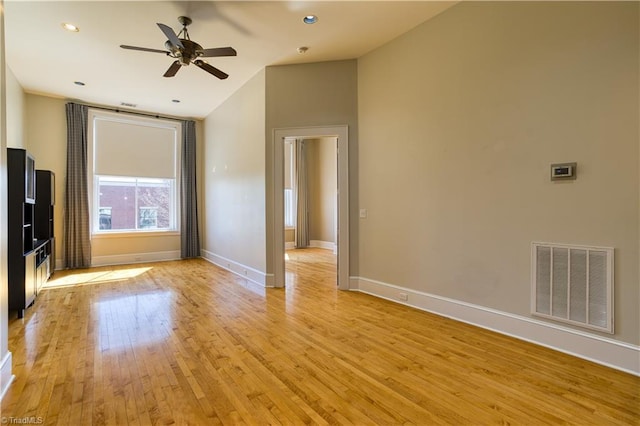 unfurnished living room featuring light wood finished floors, visible vents, baseboards, vaulted ceiling, and a ceiling fan