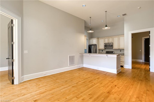 kitchen with light wood finished floors, visible vents, cream cabinetry, and stainless steel appliances