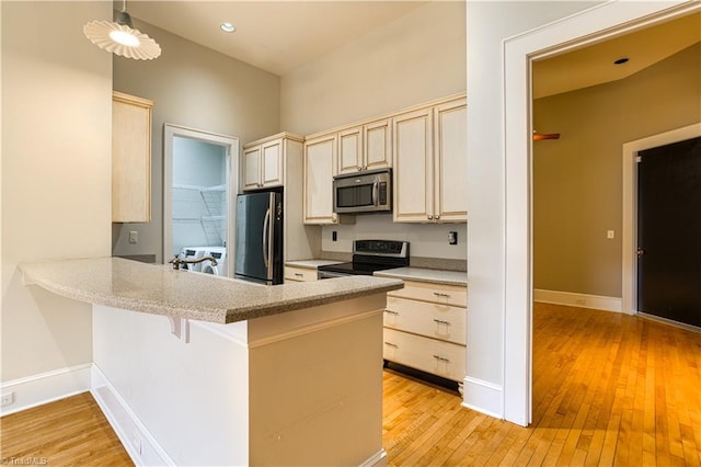 kitchen with a peninsula, stainless steel appliances, light wood-type flooring, and light countertops