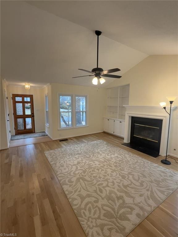 unfurnished living room featuring plenty of natural light, light hardwood / wood-style floors, ceiling fan, and vaulted ceiling