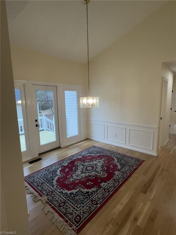 dining area featuring a chandelier, high vaulted ceiling, and hardwood / wood-style floors