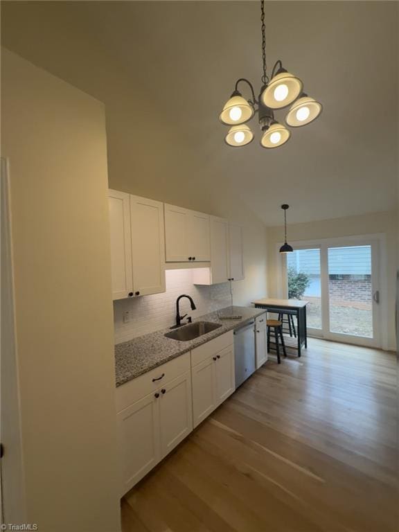 kitchen featuring decorative light fixtures, tasteful backsplash, dishwasher, white cabinetry, and sink