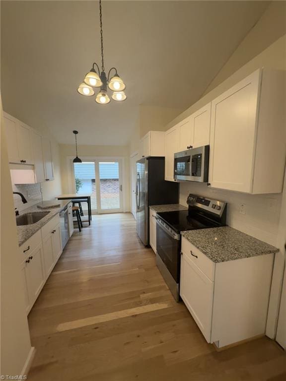 kitchen featuring white cabinetry, appliances with stainless steel finishes, sink, and hanging light fixtures