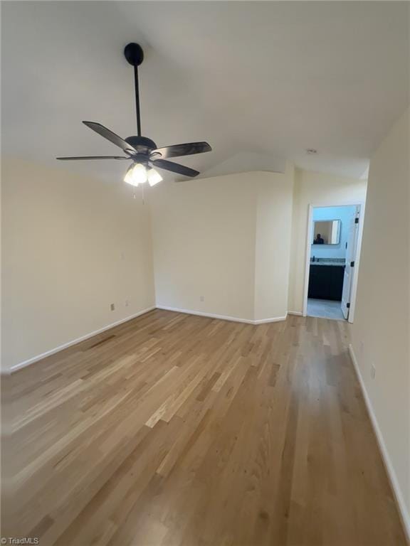 empty room with ceiling fan, lofted ceiling, and light hardwood / wood-style floors