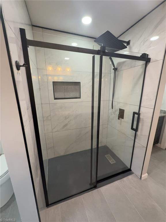 bathroom featuring toilet and a shower with shower door