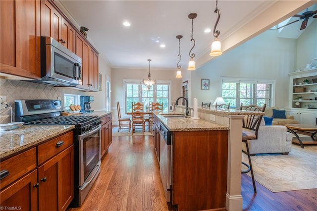 kitchen featuring a kitchen breakfast bar, crown molding, appliances with stainless steel finishes, a sink, and open floor plan
