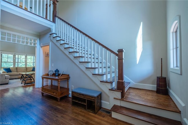 stairway with crown molding, baseboards, visible vents, and wood finished floors