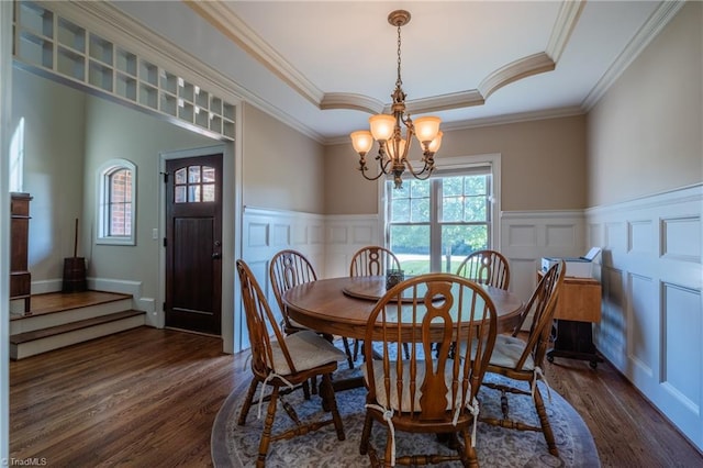 dining area with a wainscoted wall, dark wood-style floors, a chandelier, ornamental molding, and a decorative wall