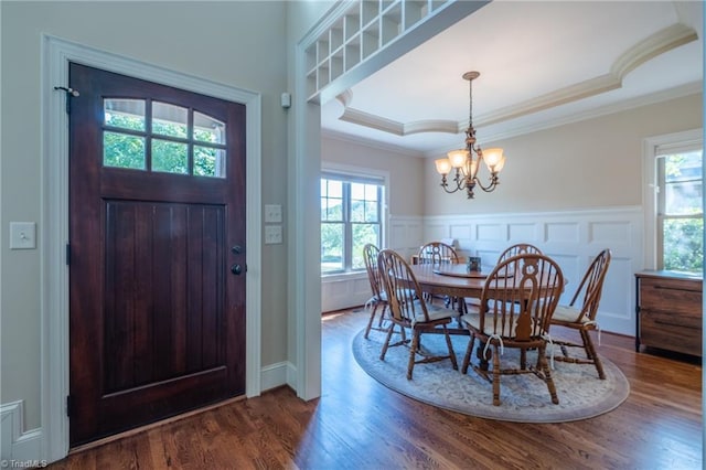 entrance foyer with a notable chandelier, ornamental molding, wood finished floors, and a raised ceiling