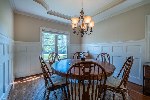 dining area featuring crown molding, wainscoting, a decorative wall, and a notable chandelier