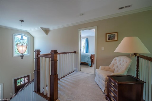 interior space featuring visible vents, ornamental molding, light colored carpet, and an upstairs landing