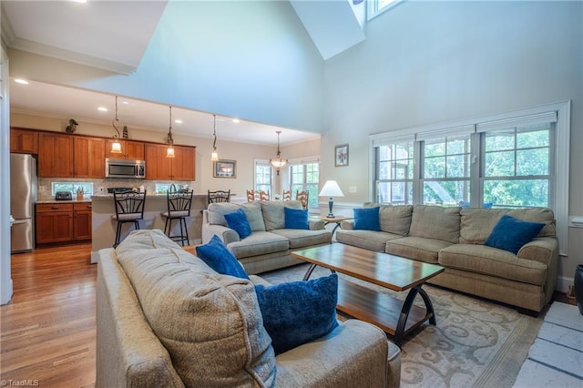 living room featuring crown molding, recessed lighting, a high ceiling, and light wood-type flooring