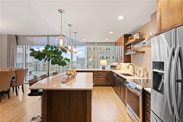 kitchen with appliances with stainless steel finishes, light hardwood / wood-style floors, a healthy amount of sunlight, and a center island