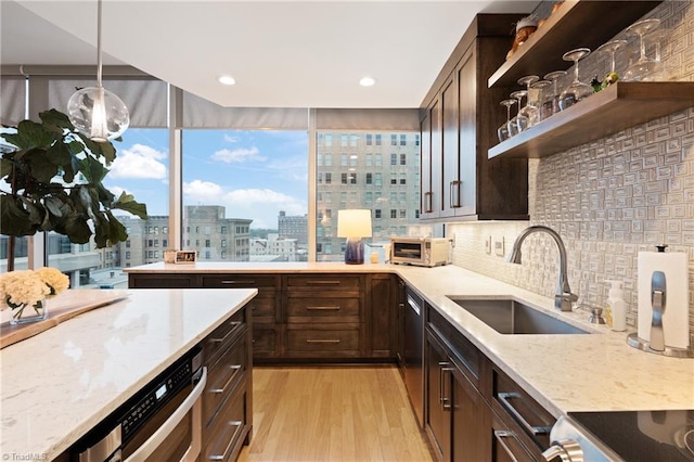 kitchen with sink, decorative light fixtures, light hardwood / wood-style flooring, stainless steel appliances, and light stone countertops